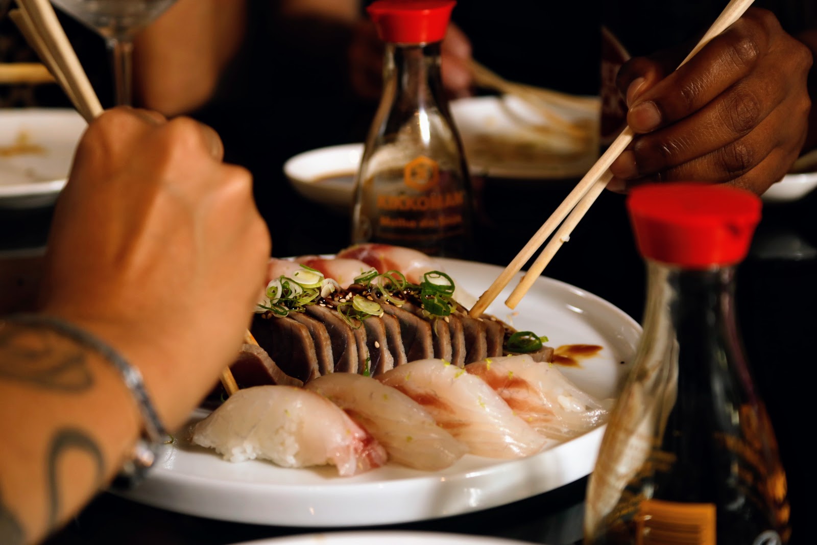 Degustação de sushi e tataki à mesa com convidados